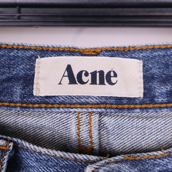 Etikett med Acne logotyp sydd på jeanstyget