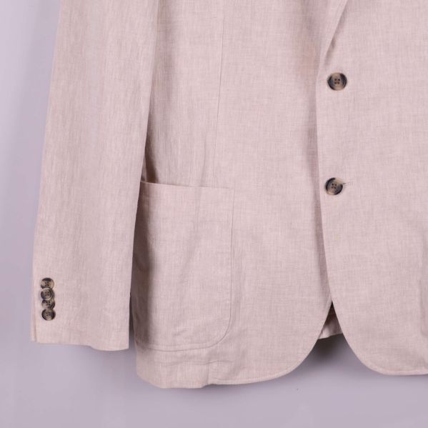 Nedre del av ärm och knappdetalj på ljusbeige kavaj