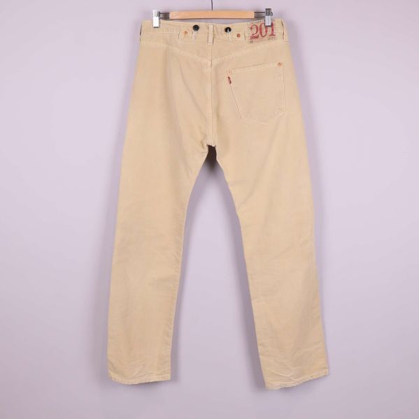 Baksida av beige jeans med patchdetaljer och ficka
