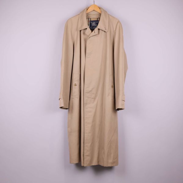 Beige lång trenchcoat på galge mot ljus bakgrund