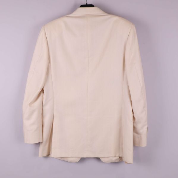 Kavajens baksida i ljust tyg upphängd på galge