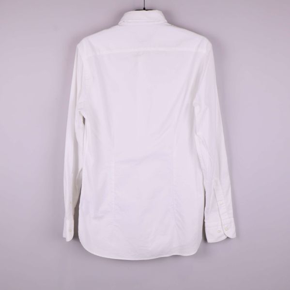 Baksidan av vit skjorta visas hängande på galge