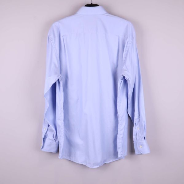 Ljusblå skjorta sedd bakifrån på galge