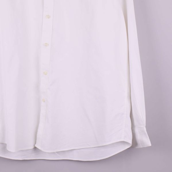 Närbild på skjortans nederkant och ärmslut i vitt tyg