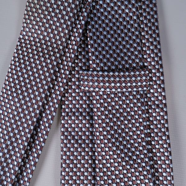 Närbild på brunt och ljusblått grafiskt mönster på slipsen