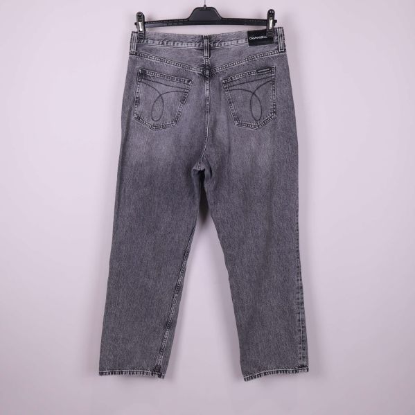 Baksida av grå jeans med dekorativa sömmar på fickorna