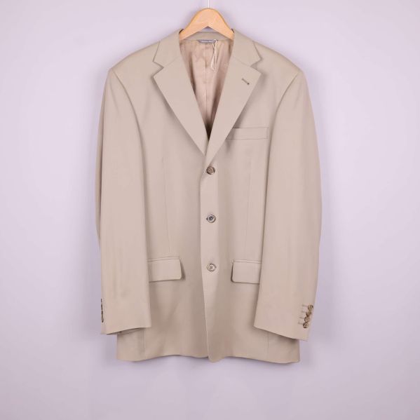 Framifrån syns beige kavaj med slag och fickor