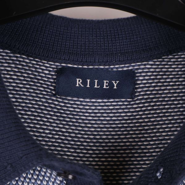 Närbild på Riley-märket i kragen på pikétröjan