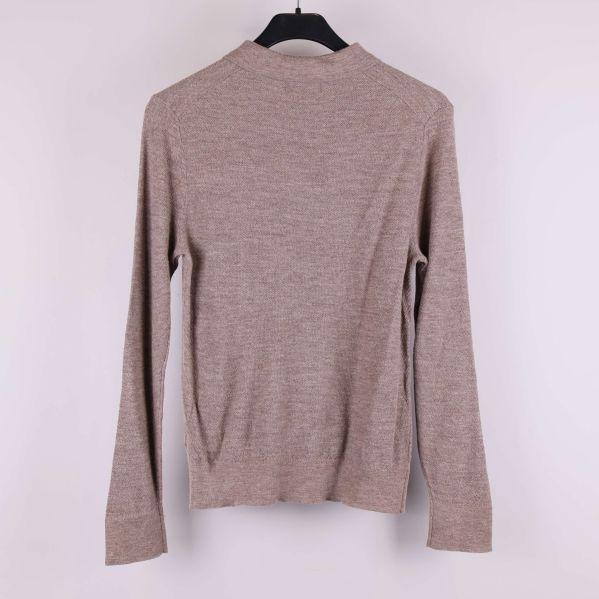 Baksidan av beige stickad tröja med långa ärmar