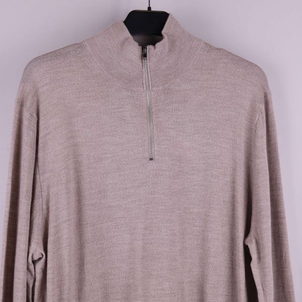 Närbild på dragkedja och halvpolo av beige stickad tröja