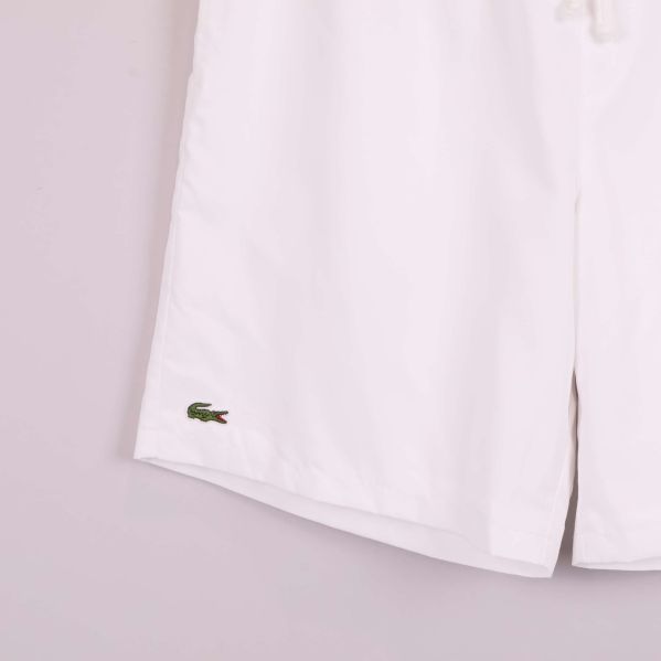 Närbild på Lacoste-logo broderad på vänster ben