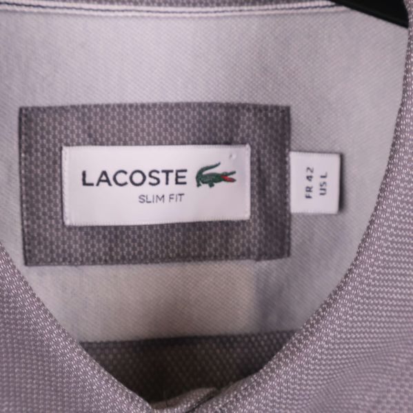 Närbild på Lacoste-märkesetikett och storleksskylt inuti skjortan