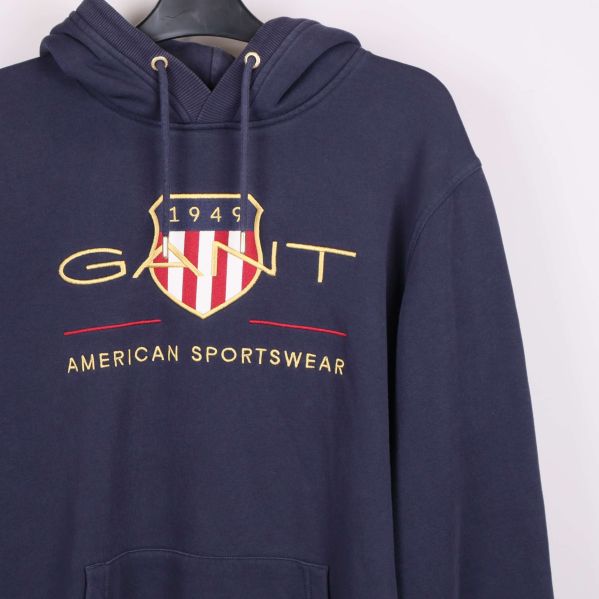 Närbild på logotyp och tryckdetalj framtill på mörkblå hoodie