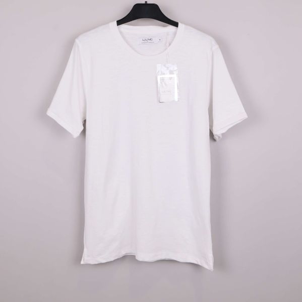 Vit t-shirt på galge mot ljus bakgrund