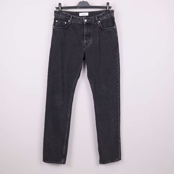 Framsida av svarta raka jeans hängande mot ljus bakgrund