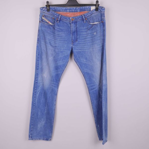 Framsidan av blå slitna slim jeans på galge