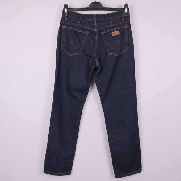 Baksida av mörkblå jeans med fickor och guldbroderi