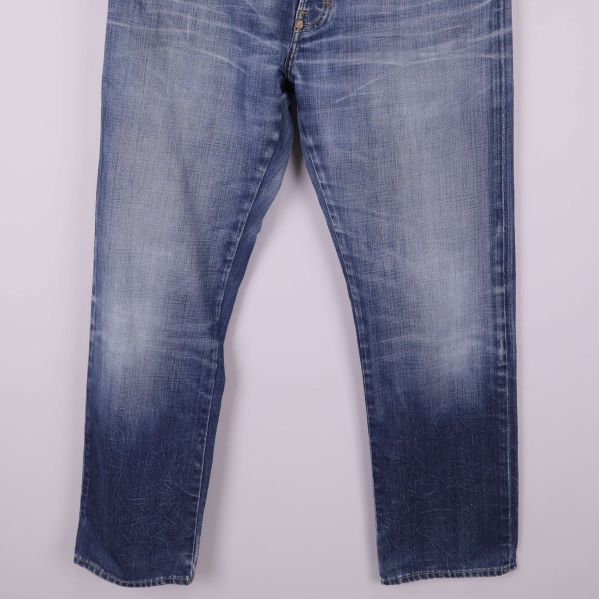 Lågdelsvy av jeans med synliga slitningar vid benslut