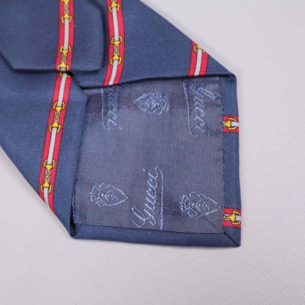 Närbild på slipsens spets med vävd Gucci-logo