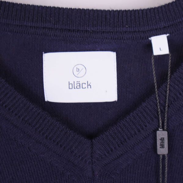 Närbild på etikett med bläck-logotyp framtill i nacken