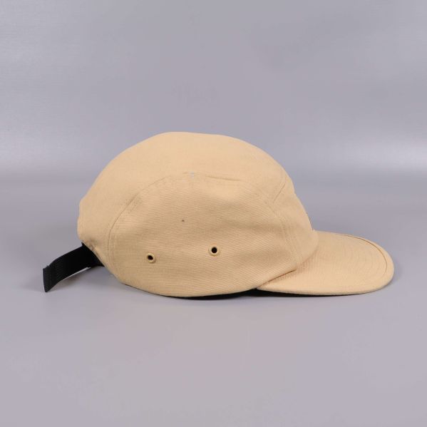 Beige keps sedd från sidan med ventilationshål och justerbar rem baktill