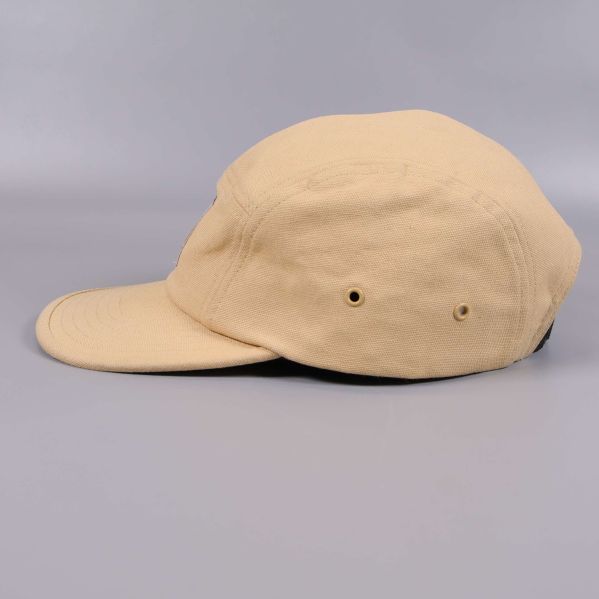 Beige keps sedd i profil med detaljerade sömmar och hål