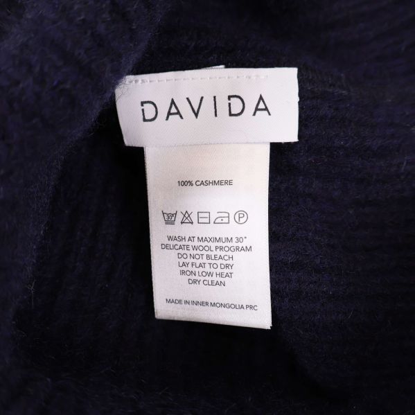 Närbild på inneretikett som visar Davida och materialangivelsen 100% kashmir