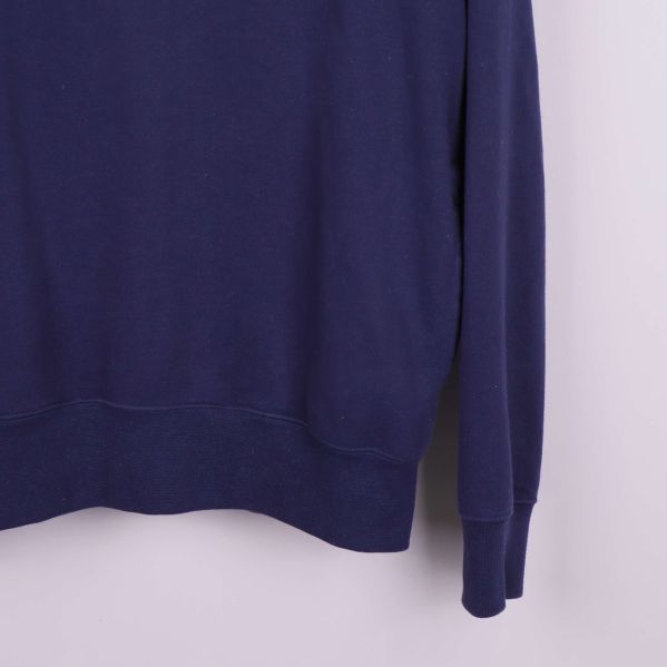 Närbild på nederkant och ärmslut av marinblå hoodie