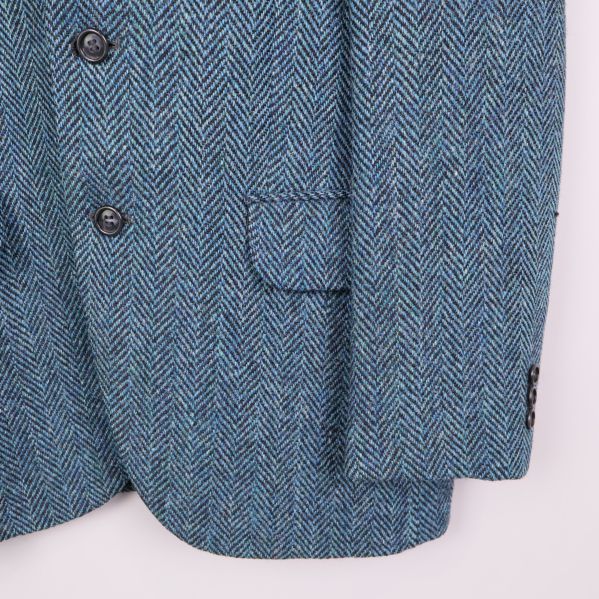 Fickdetalj och ärm på kavajen i blå tweed