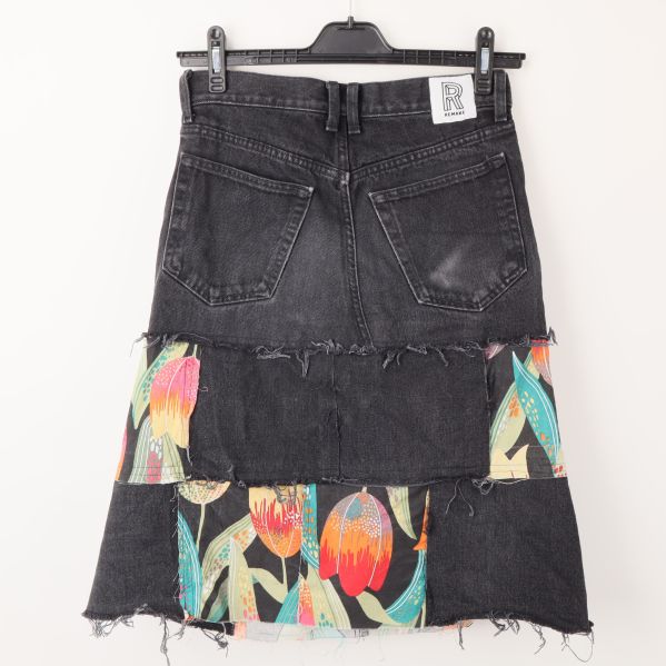 Baksida av svart denimkjol med färgglada inslag