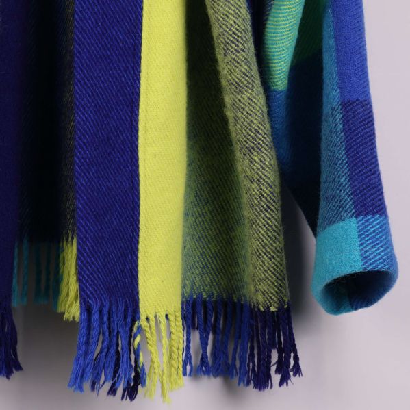 Närbild av koftans nederkant med blå och gula fransar