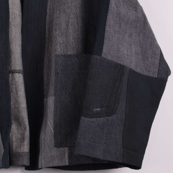 Närbild på kimonoärm och ficka i olika denimtyger