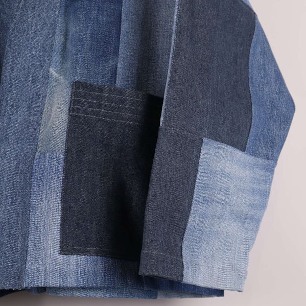 Närbild på jackans framficka i mörk denim
