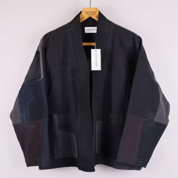 Kimonojacka i mörkt patchwork-mönster hängande på galge