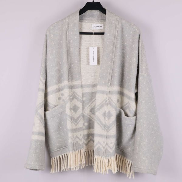 Framsida av ljusgrå cardigan med vita mönster och fransar
