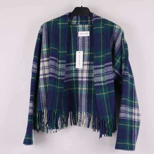 Rutig jacka med öppen front och fransar hänger på galge