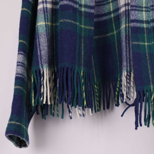 Närbild på nederkant med fransdetaljer på rutmönstrad jacka