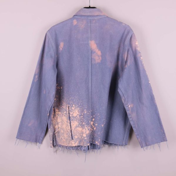 Baksidan av jacka i blått tyg med ljusa fläckar och frans