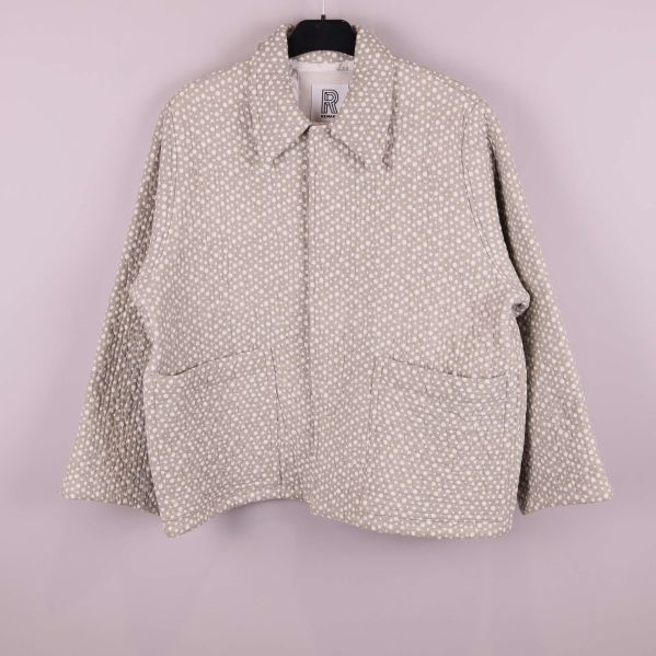 Framsida av prickig quiltad jacka på galge