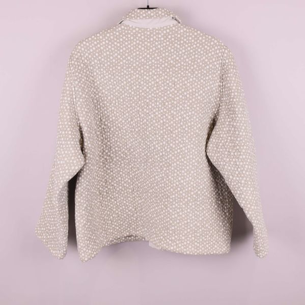 Baksida av beige quiltad jacka med prickar