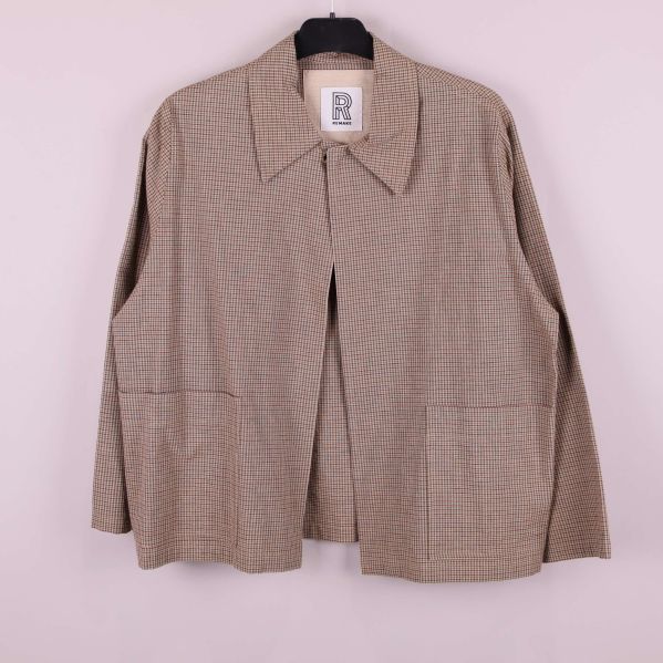 Rutig jacka med öppen framsida och fickor hänger på galge