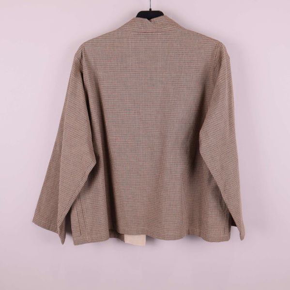 Baksidan av rutig jacka på galge mot ljus bakgrund