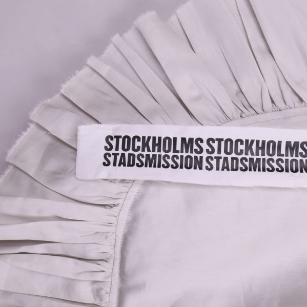 Närbild på volangkant och textband på axelväska