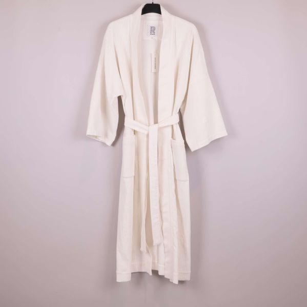 Vit kimono med skärp på galge mot ljus bakgrund