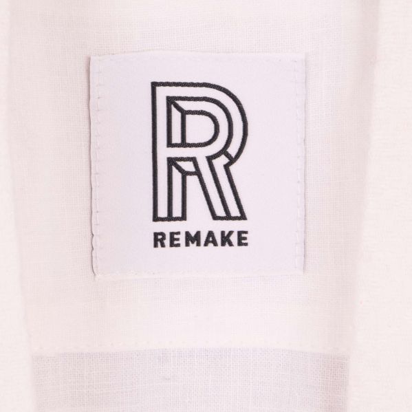 Närbild på Remake-logotyp på vit linnemorgonrock