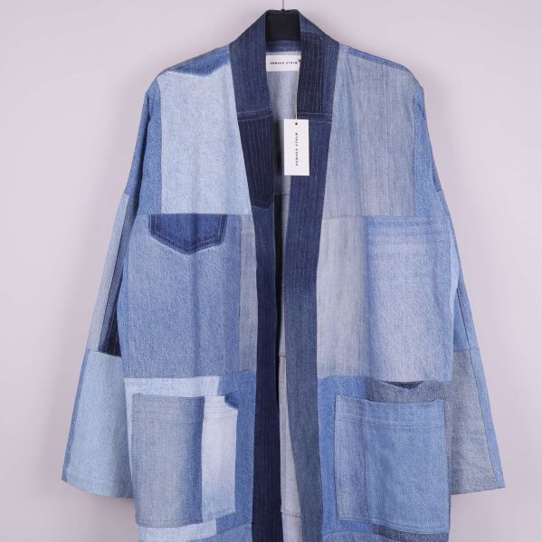 Närbild på kappans öppning och fickor i mixat denim