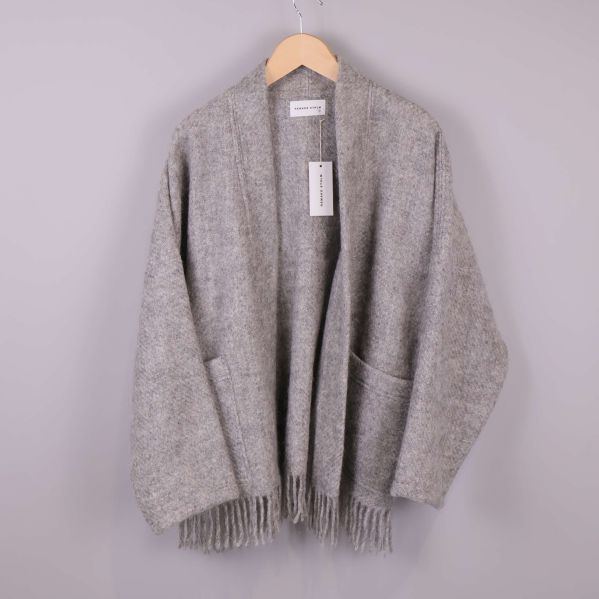 Grå stickad kimono med fransar hänger på galge