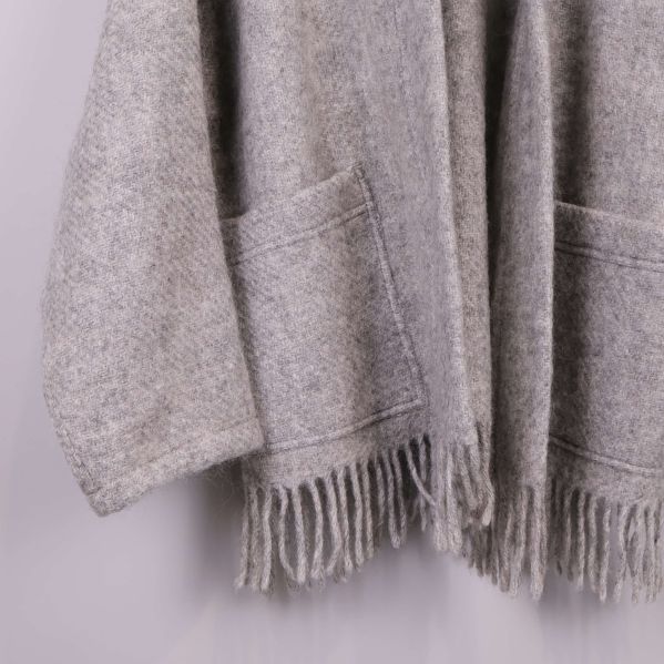 Närbild på fickor och fransar på grå stickad kimono