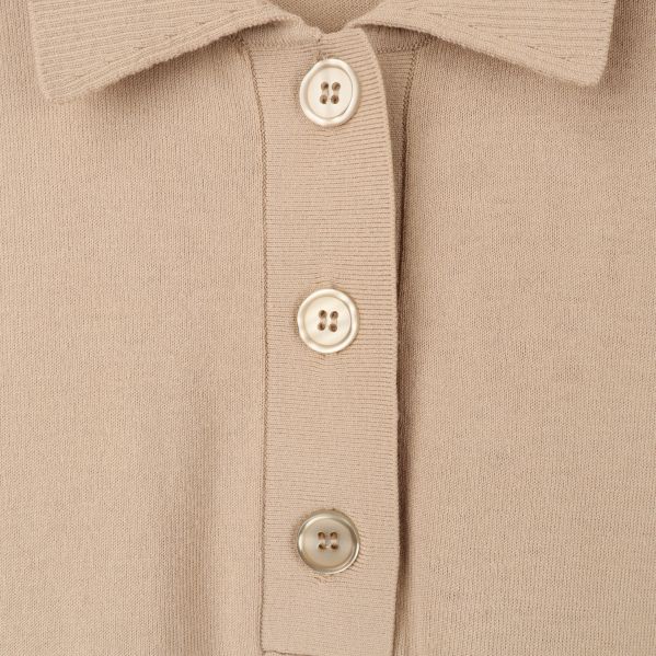 Närbild av knappar på beige polotröja