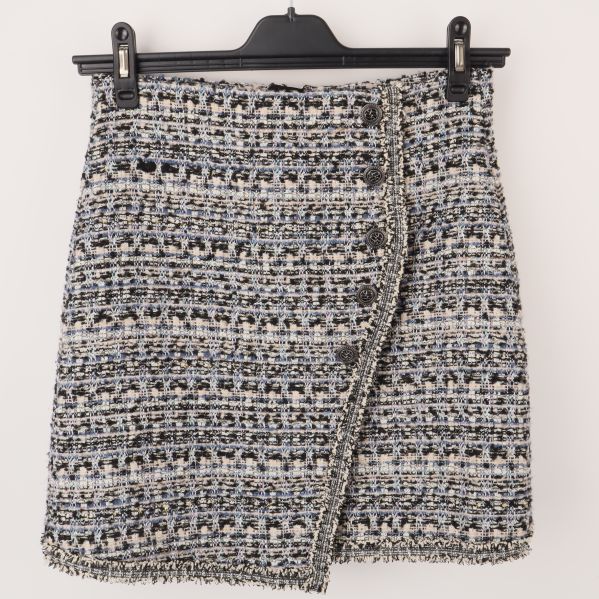 Framsidan av en flerfärgad tweedkjol med knappdetaljer